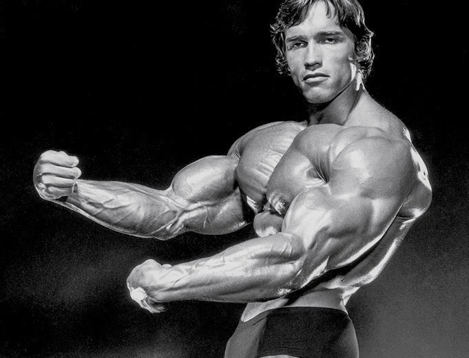 Arnold Schwarzenegger flexing his massive upper arms and triceps in a classic black-and-white bodybuilding pose