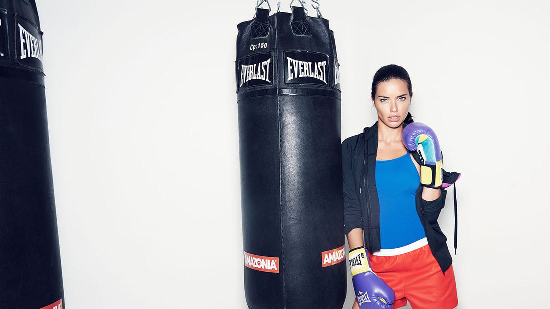Adriana Lima training in boxing gloves beside a heavy bag
