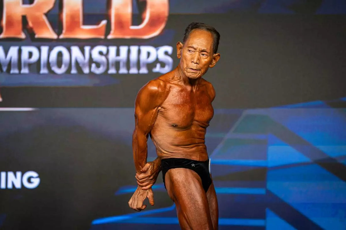 Toshisuke Kanazawa, age 90, posing onstage at the 2026 IFBB World Fitness and Bodybuilding Championships in Spain
