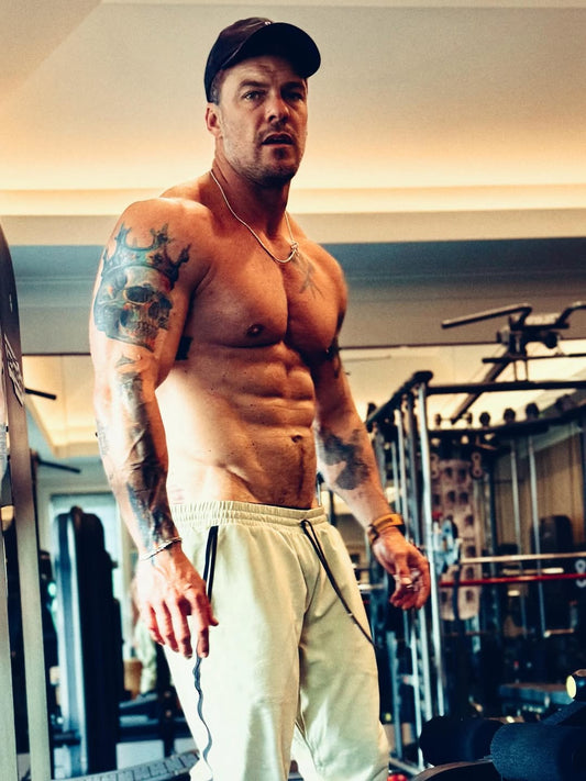Alan Ritchson in a gym showing his muscular physique