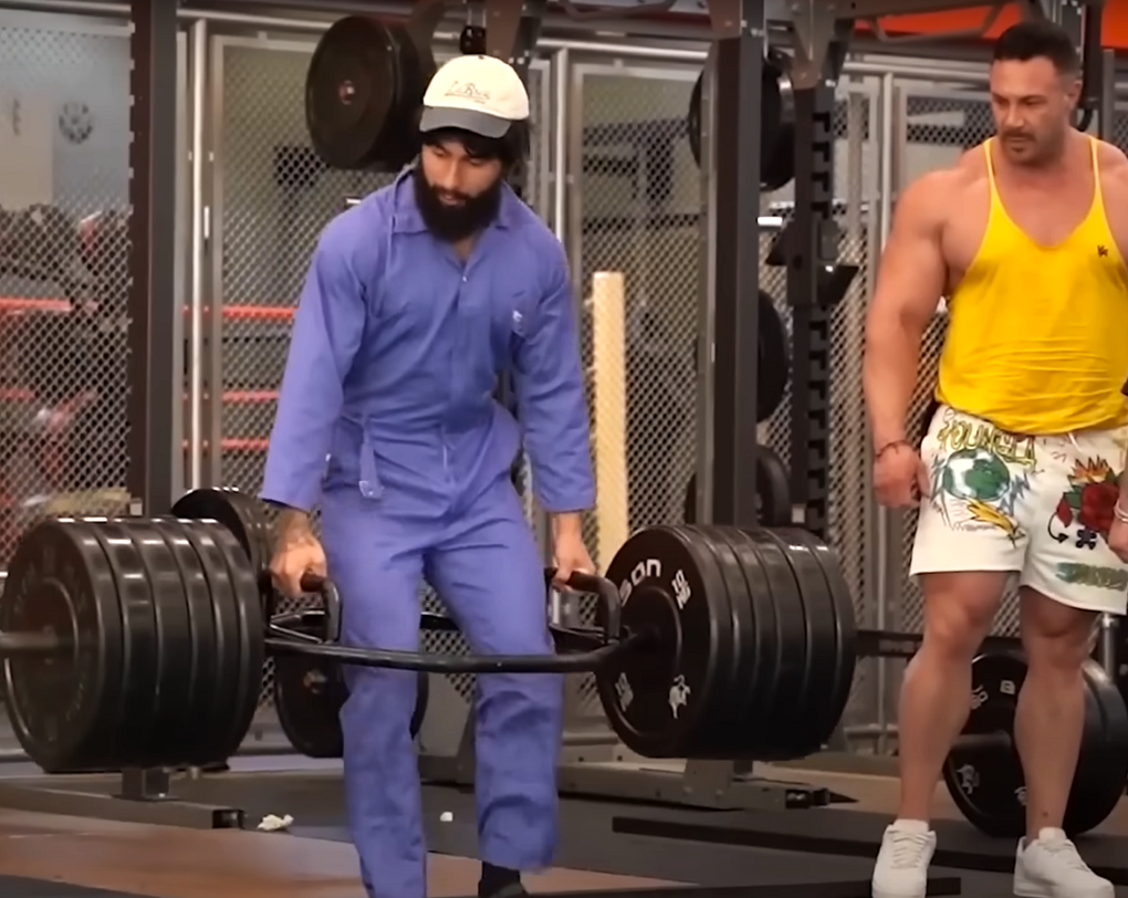 Anatoly in blue cleaner overalls lifting in a commercial gym