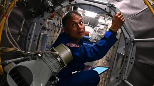 NASA astronaut Anil Menon in a blue flight suit inside a spacecraft-style module