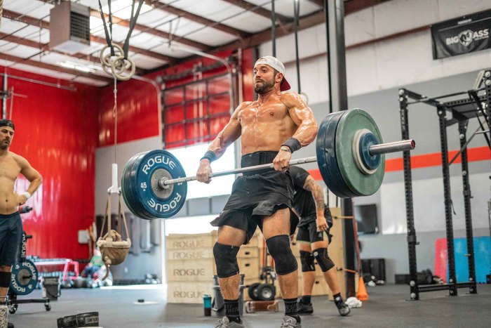 CrossFit athlete power cleaning a barbell in a training gym