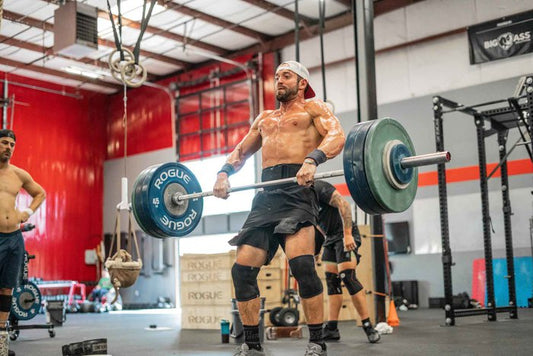CrossFit athlete power cleaning a barbell in a training gym