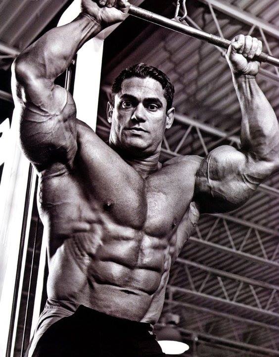 Gustavo Badell training at a lat pulldown machine in a black-and-white bodybuilding photograph