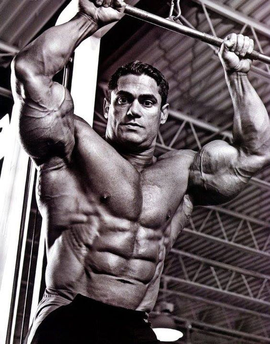 Gustavo Badell training at a lat pulldown machine in a black-and-white bodybuilding photograph