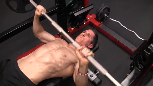 Jeff Cavaliere performing a barbell bench press in the ATHLEAN-X training gym