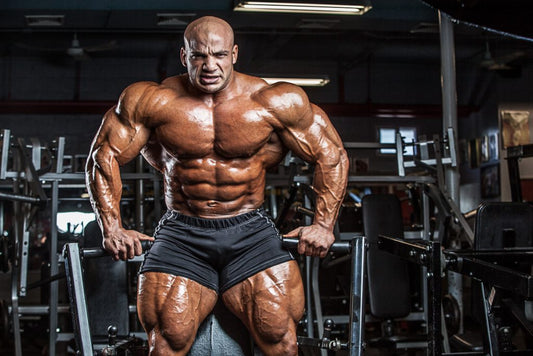 Big Ramy in a gym with his muscular physique visible beside weight machines