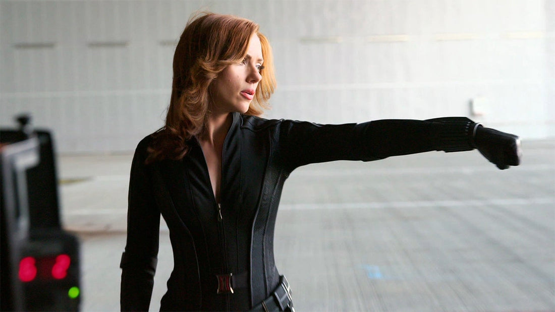 Scarlett Johansson as Black Widow in a black tactical suit extending an arm in a combat stance