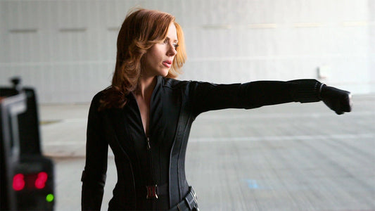 Scarlett Johansson as Black Widow in a black tactical suit extending an arm in a combat stance
