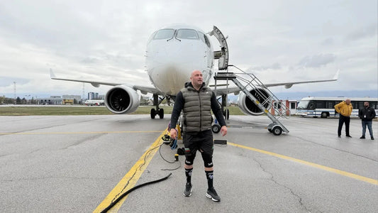 Hristo Muskov standing in front of a passenger jet at Sofia Airport during preparations for an airplane-pull challenge