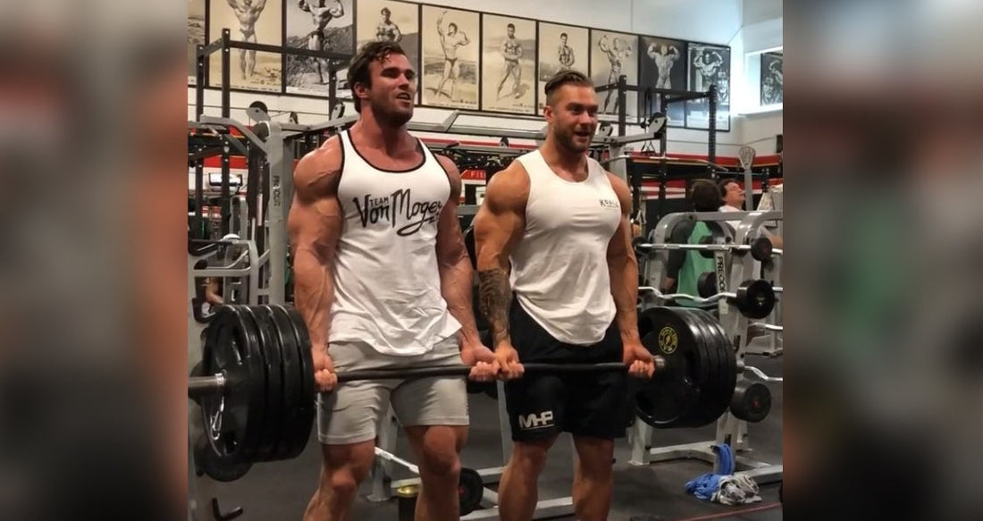 Calum Von Moger and Chris Bumstead curling a heavily loaded barbell together at Gold's Gym Venice in 2017