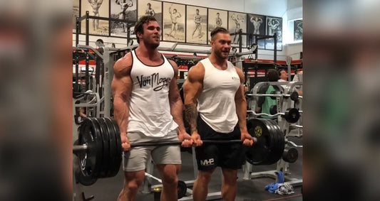 Calum Von Moger and Chris Bumstead curling a heavily loaded barbell together at Gold's Gym Venice in 2017
