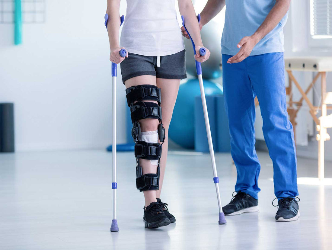 A patient using crutches while wearing a rigid knee immobilizer in a rehabilitation clinic