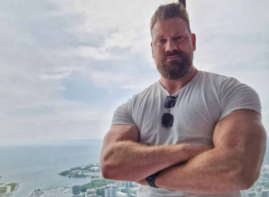 Olivier Richters, the Dutch Giant, standing with muscular arms folded above a coastal city