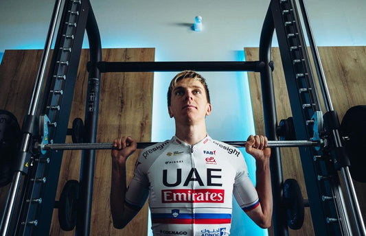 Tadej Pogačar performing a barbell squat in a UAE Team Emirates cycling jersey