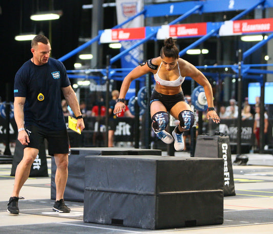 CrossFit athlete performing a powerful box jump in competition