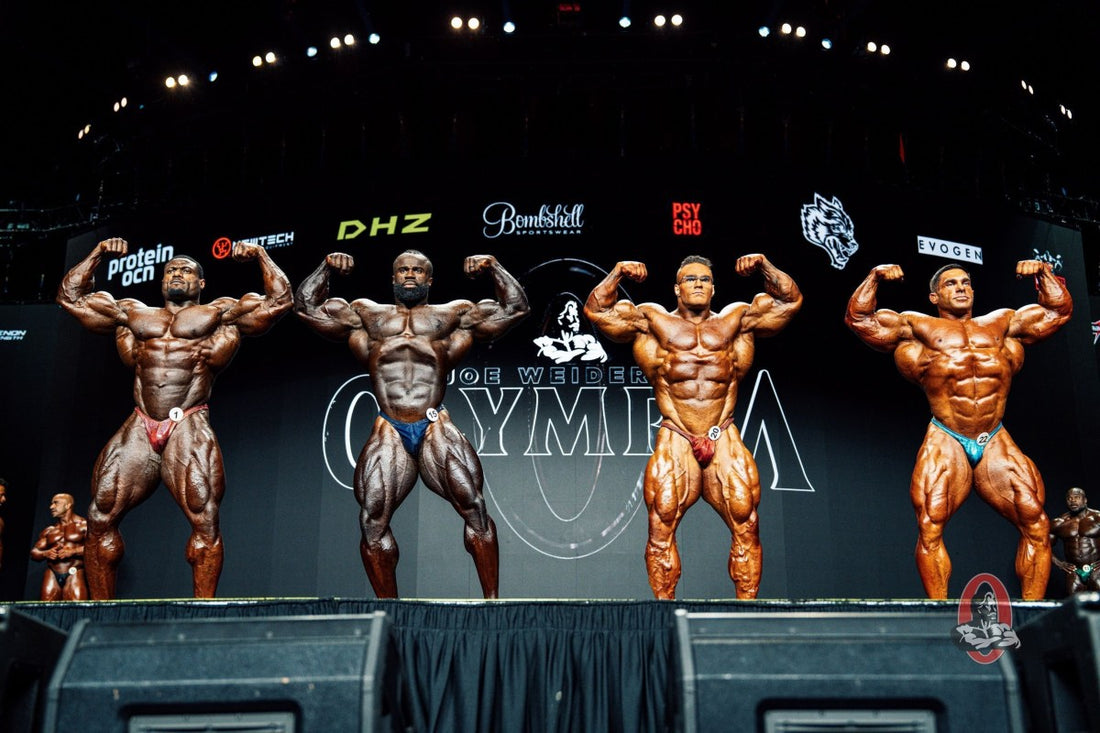 Four elite Men's Open bodybuilders posing side by side in a front double-biceps comparison at the 2026 Mr. Olympia