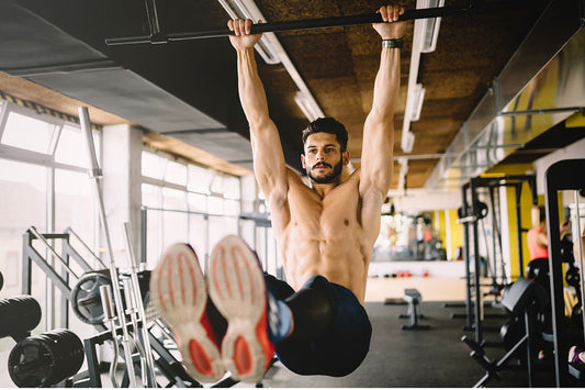 Athlete performing a controlled hanging leg raise in a gym, illustrating advanced core training