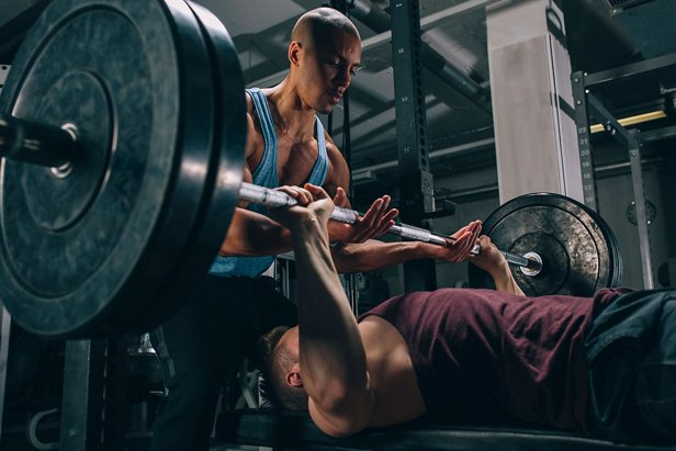 Powerlifter bench pressing a loaded barbell with an attentive spotter