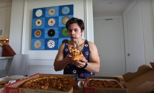 Will Tennyson holding a large pizza slice during a high-calorie food challenge