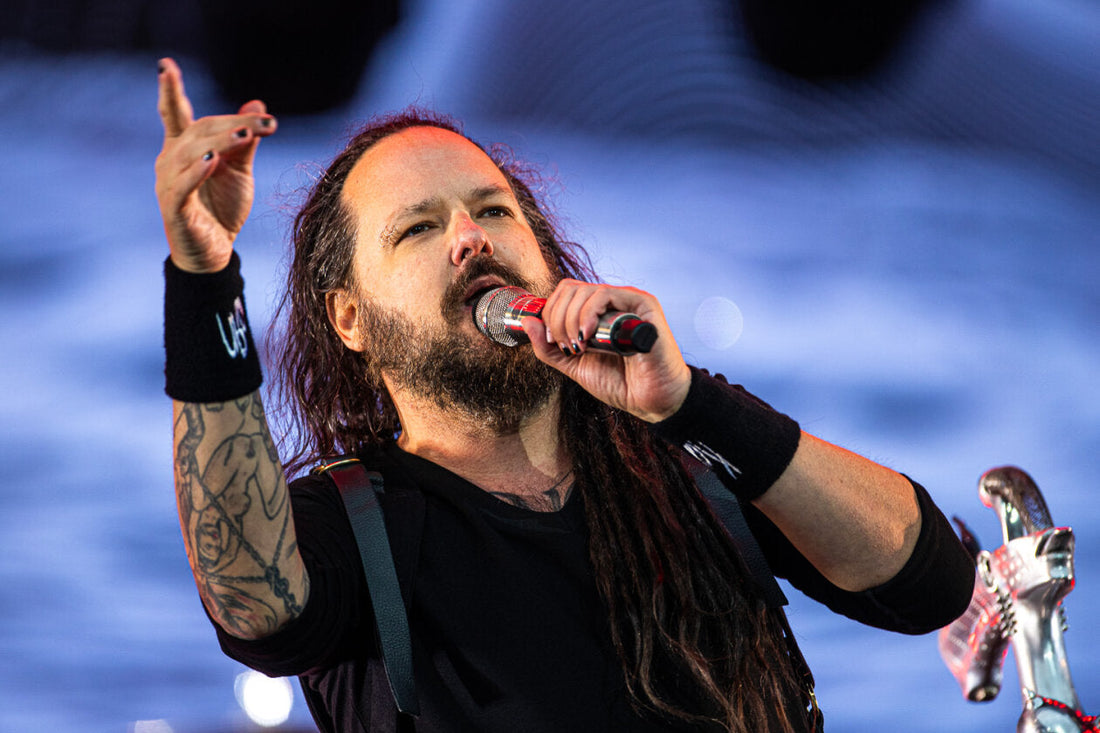 Jonathan Davis of Korn performing live at Rock am Ring 2022 with a microphone and tattooed arm raised