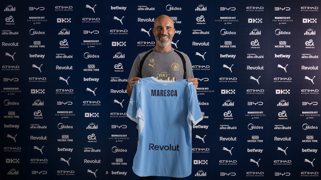 Enzo Maresca holding a Manchester City shirt after becoming City manager in 2026
