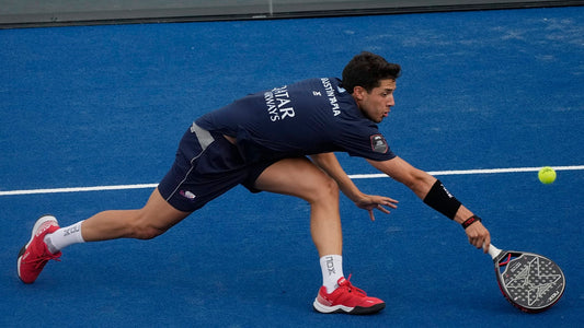 Agustín Tapia stretching to return a ball on a professional padel court