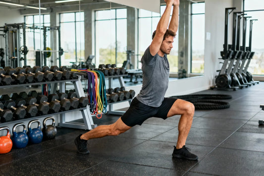 Male athlete performing a controlled deep overhead lunge mobility stretch in a gym