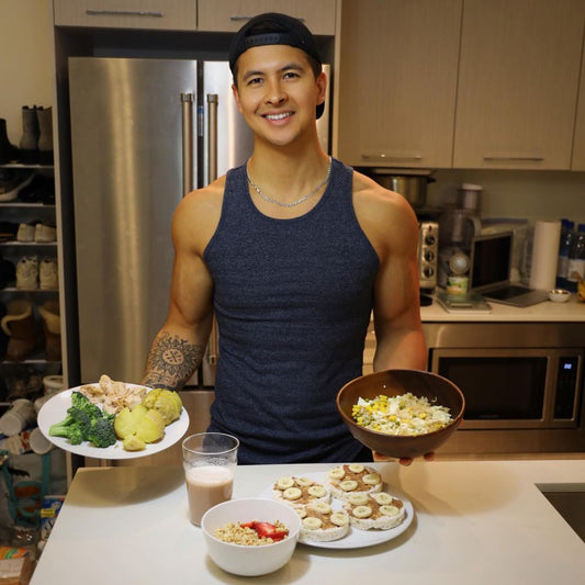 Jeremy Ethier smiling in a kitchen while holding two balanced meals