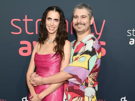 Ethan and Hila Klein together at a red-carpet event, Hila in a pink gown and Ethan in a colorful shirt