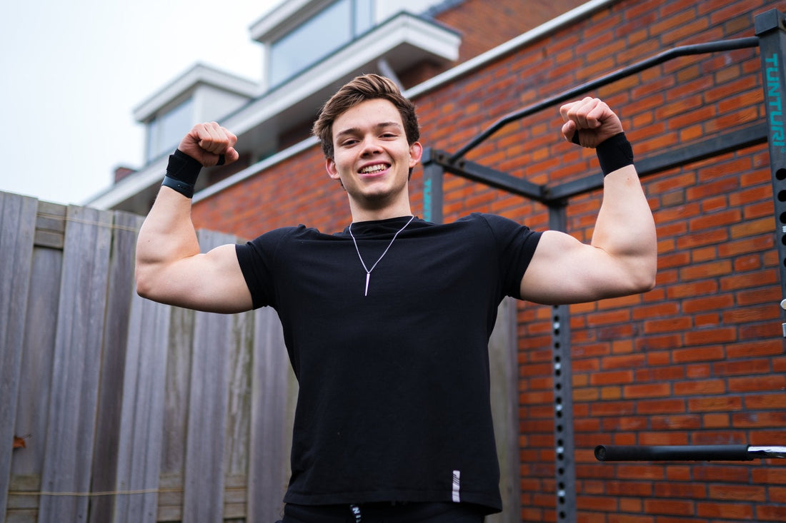 Stan Browney flexing his arms beside a backyard calisthenics pull-up rig