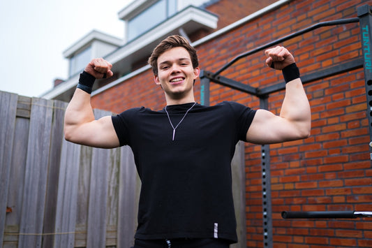 Stan Browney flexing his arms beside a backyard calisthenics pull-up rig