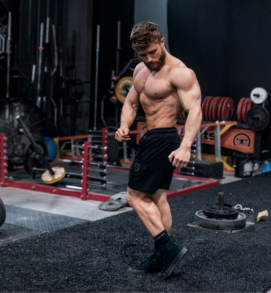 Jeff Nippard shirtless in a weight room showing muscular abdominal definition