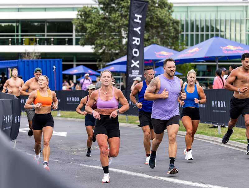 HYROX athletes in sleeveless training tops running outdoors at the Auckland fitness race