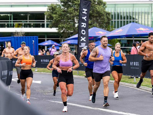 HYROX athletes in sleeveless training tops running outdoors at the Auckland fitness race