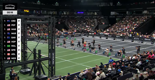 2026 Rogue Invitational CrossFit competitors performing axle-bar lifting and gymnastics on the Aberdeen competition floor