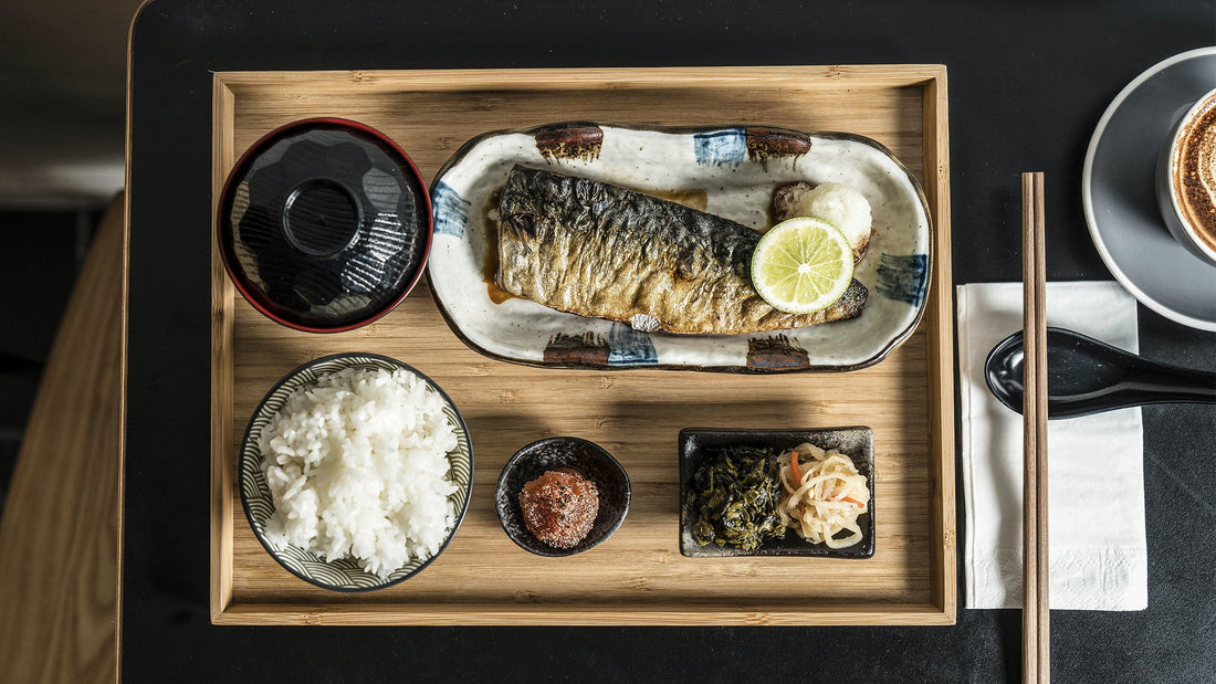Japanese-style meal of grilled fish, rice, soup and vegetable sides arranged on a wooden tray