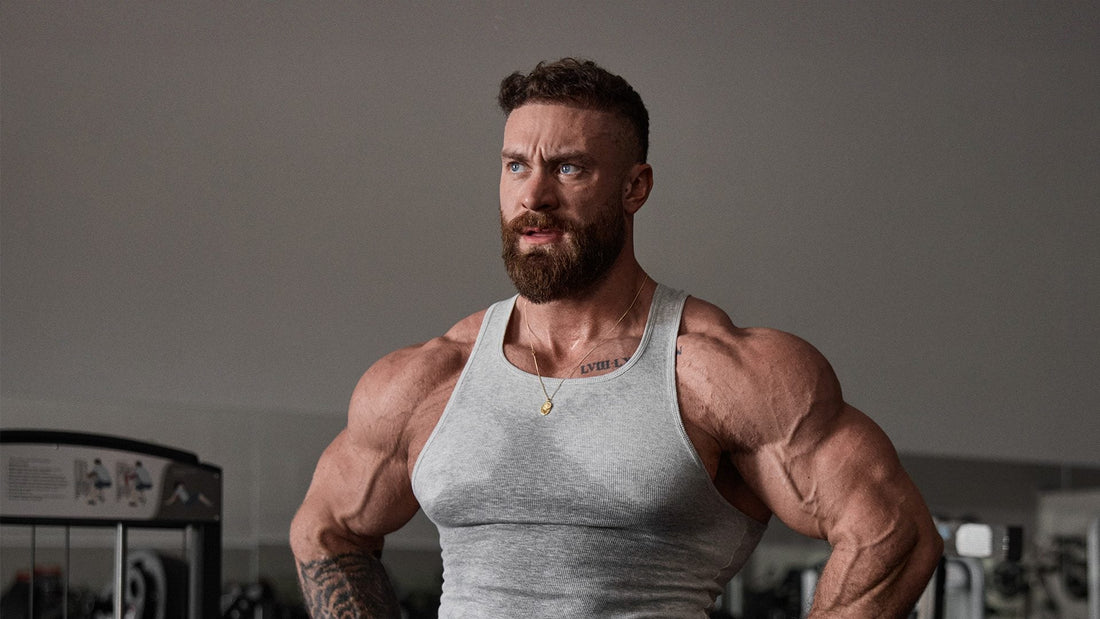 Chris Bumstead showing developed shoulders and arms in a gym, representing a rear-delt-focused bodybuilding workout