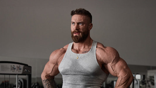 Chris Bumstead showing developed shoulders and arms in a gym, representing a rear-delt-focused bodybuilding workout