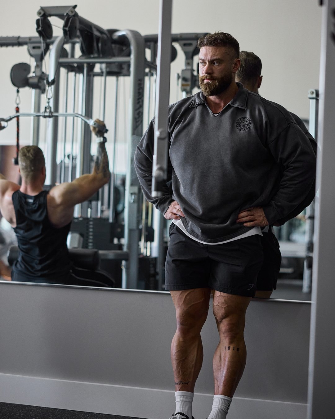 Chris Bumstead in an oversized gym sweatshirt during a bodybuilding training session