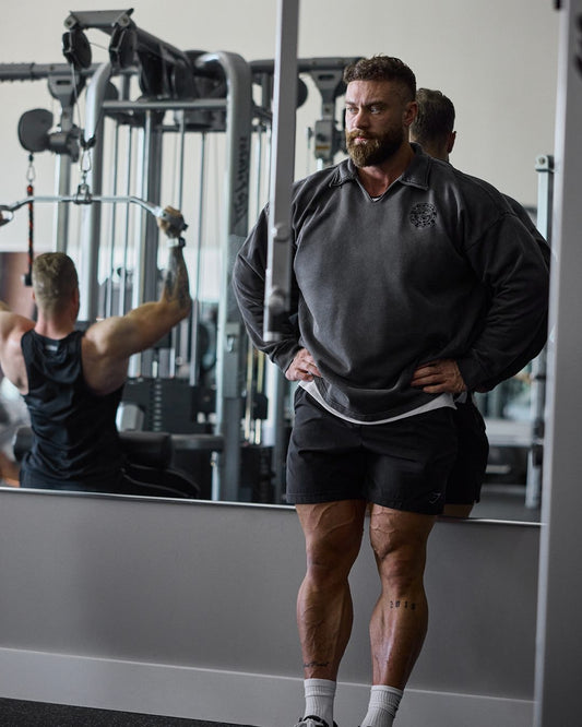 Chris Bumstead in an oversized gym sweatshirt during a bodybuilding training session