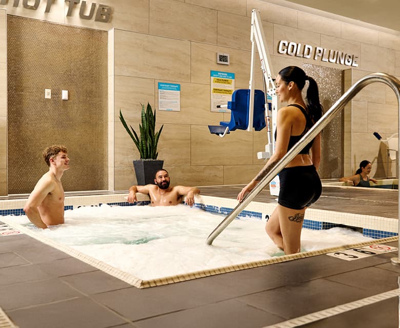 Fitness club recovery area with hot tub and cold plunge facilities illustrating ice baths versus heat after training.