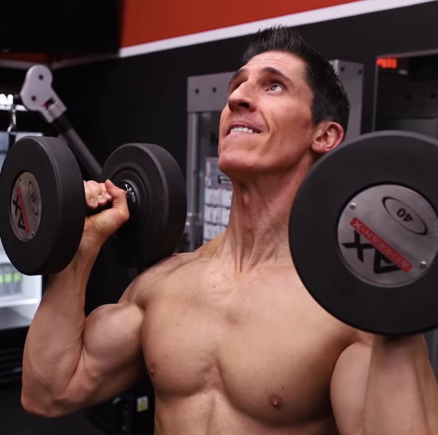 Jeff Cavaliere preparing a dumbbell shoulder press in a gym