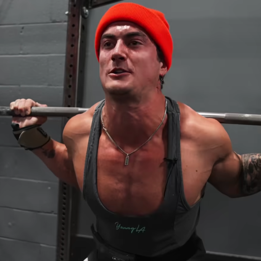 Jesse James West bracing under a barbell in an intense powerlifting training challenge