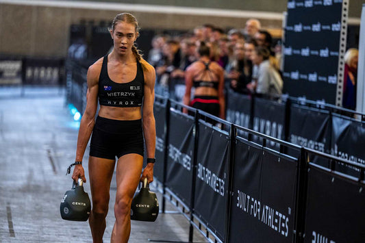 Joanna Wietrzyk carrying kettlebells on a HYROX indoor race course