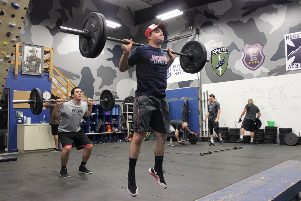 Athletes performing loaded jump squats in a gym during explosive lower-body training