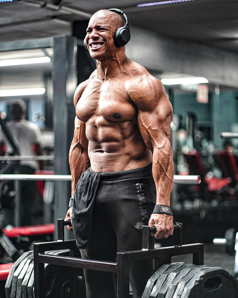 Muscular lifter training with over-ear headphones in a gym