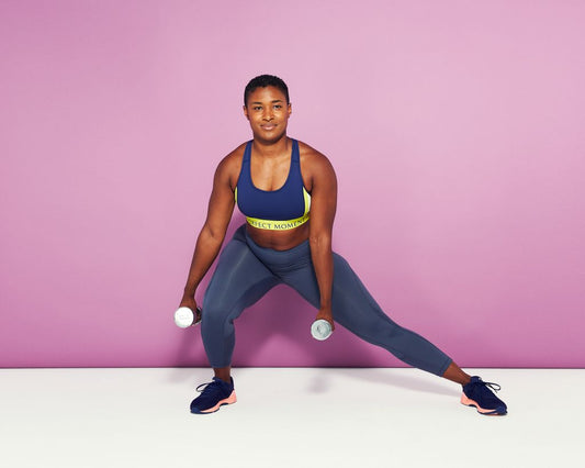 Female athlete performing a controlled lateral dumbbell lunge in a fitness studio