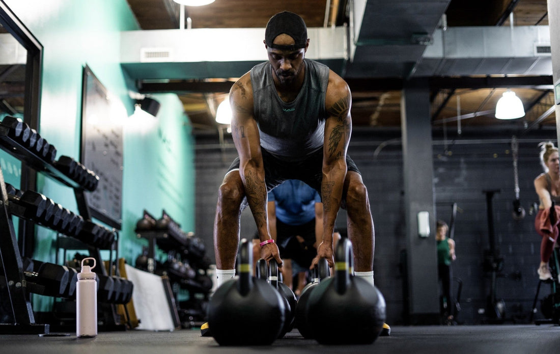 Athlete setting up two kettlebells for a strength workout in an industrial gym